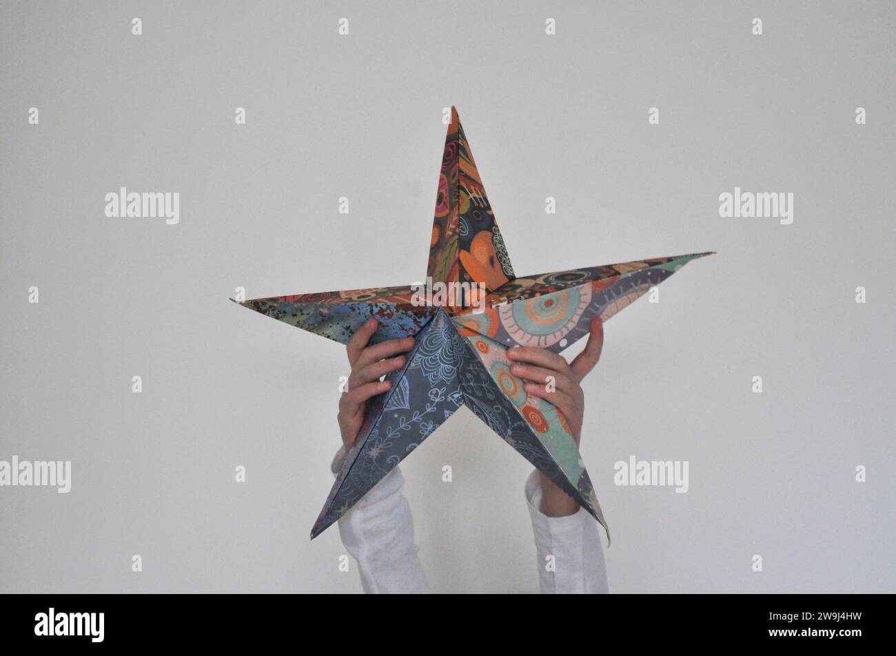 Une photo de studio d'une jeune fille tenant une décoration de Noël étoile en origami sur un fond blanc Banque D'Images
