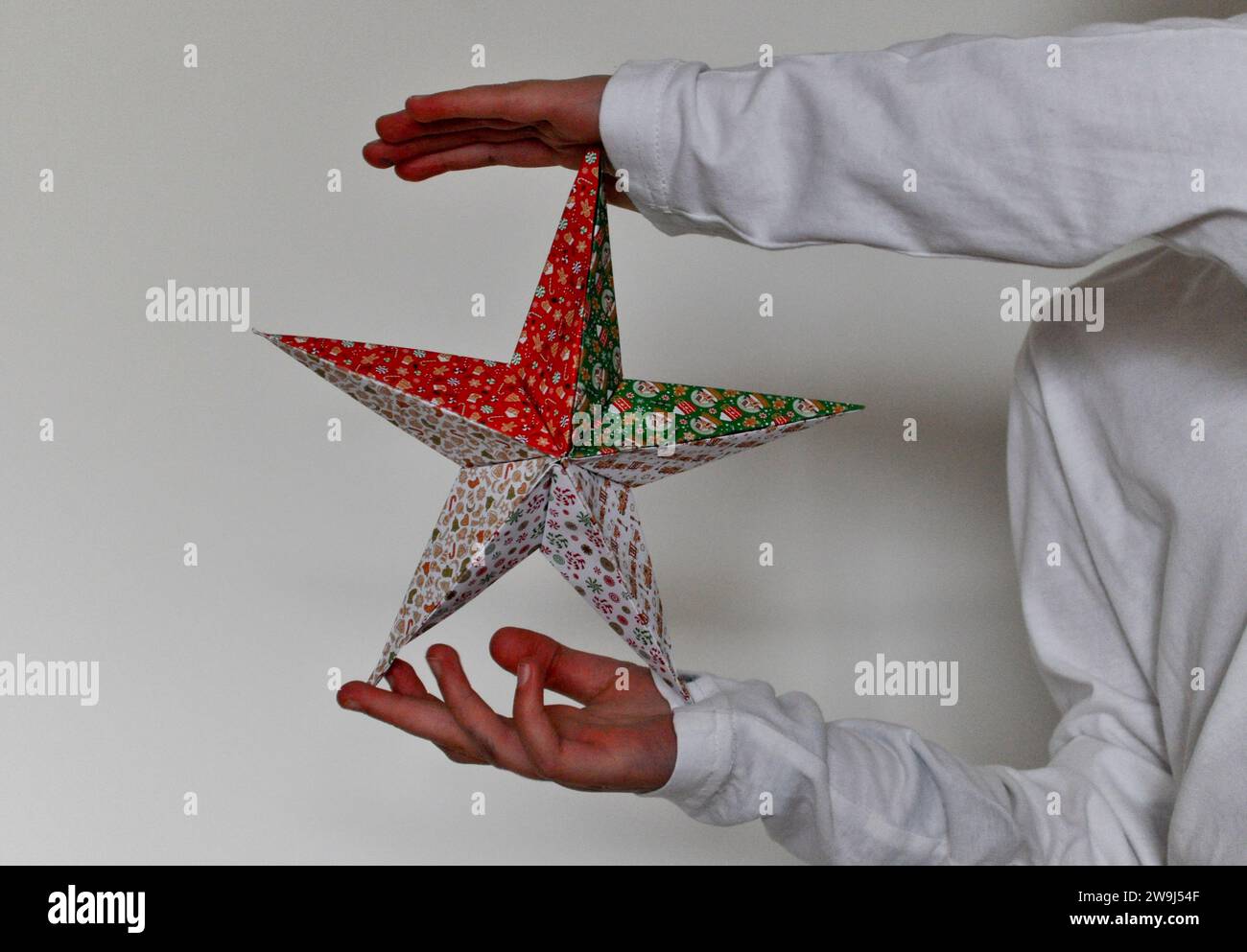 Une photo de studio d'une jeune fille tenant une décoration de Noël étoile en origami sur un fond blanc Banque D'Images