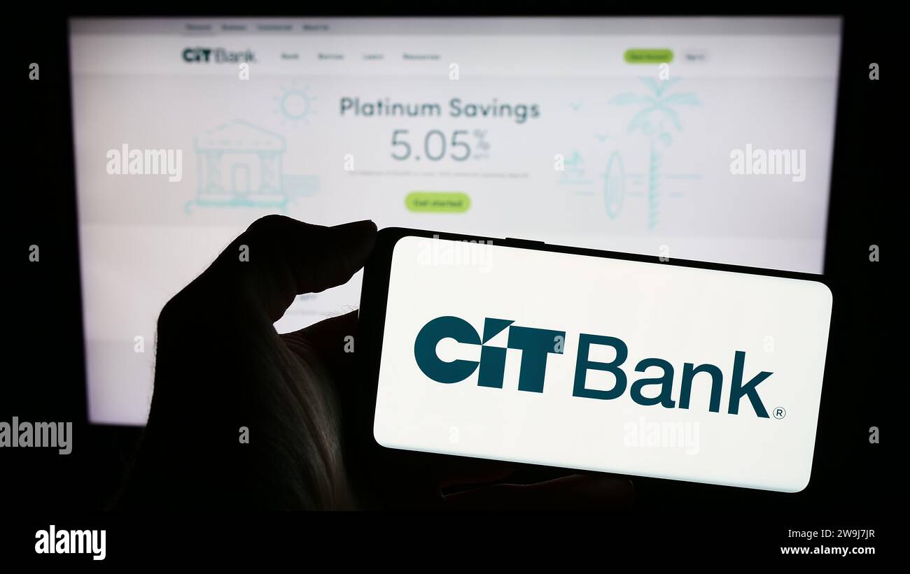 Personne tenant le téléphone mobile avec le logo de la société américaine de services financiers CIT Bank en face de la page Web d'affaires. Concentrez-vous sur l'affichage du téléphone. Banque D'Images