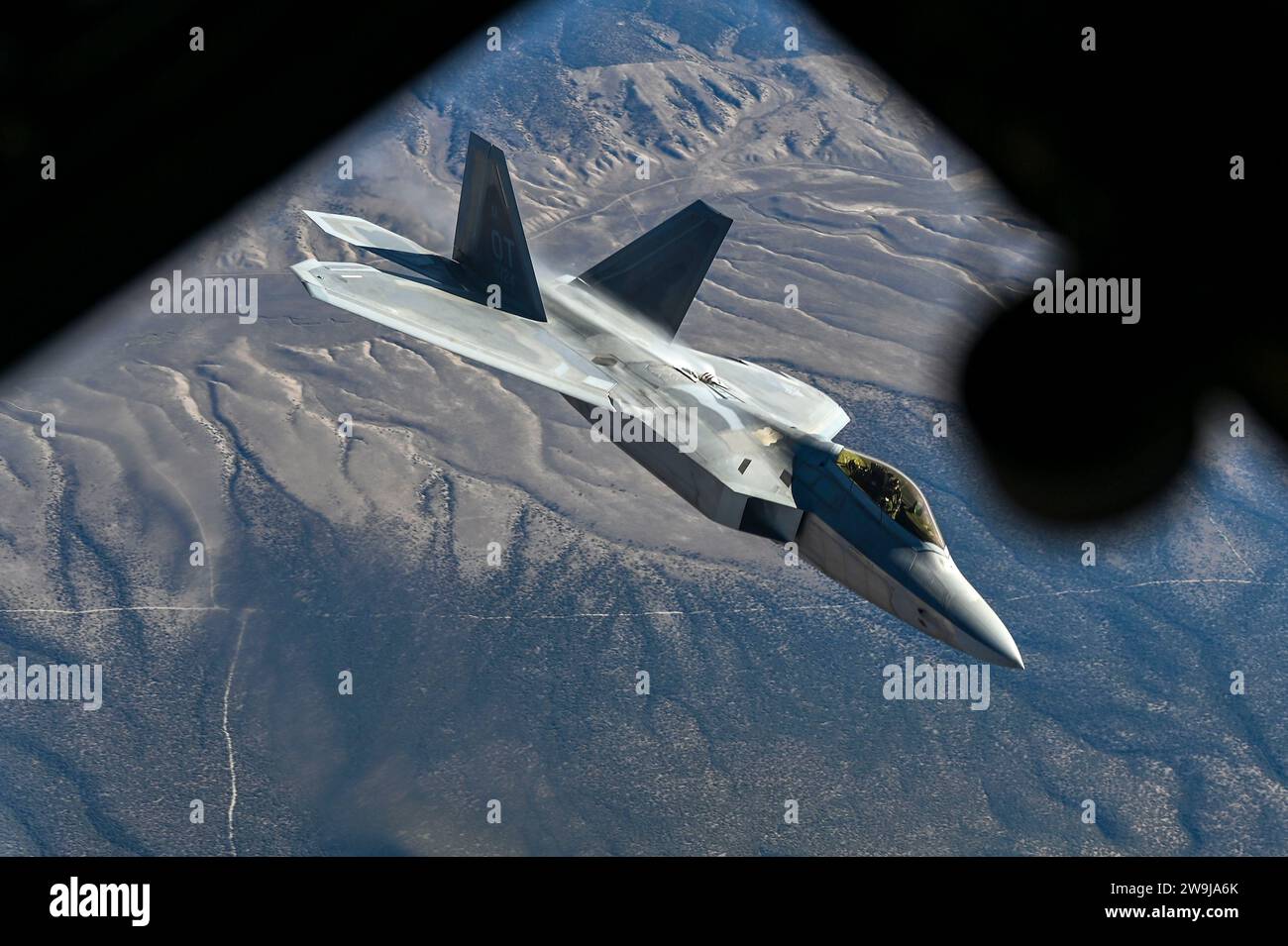 Base aérienne de Nellis, États-Unis. 12 décembre 2023. Un avion de chasse furtif F-22 Raptor de l'US Air Force s'interrompt après avoir été ravitaillé en vol par un USAF KC-135 Stratotanker pendant le cours d'intégration d'armes sur le champ d'essai et d'entraînement du Nevada, le 12 décembre 2023 au-dessus de la base aérienne de Nellis, Nevada. Crédit : SRA Haiden Morris/U.S. Air Force/Alamy Live News Banque D'Images