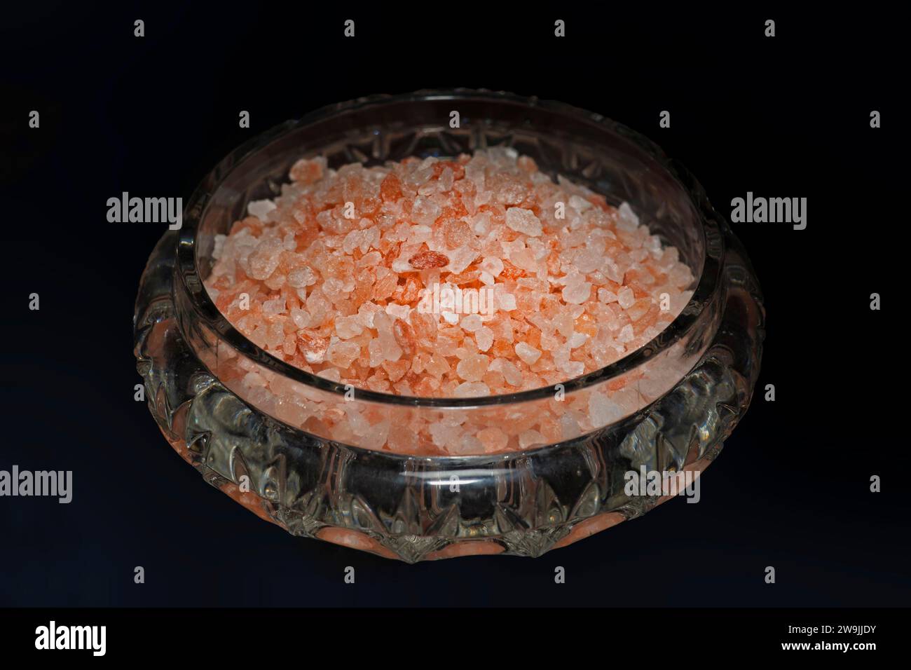 Gros sel de table rose naturel non raffiné de la région du Pendjab, Pakistan, stocké dans un bol en verre en cristal dormi, photographie de nourriture avec noir Banque D'Images