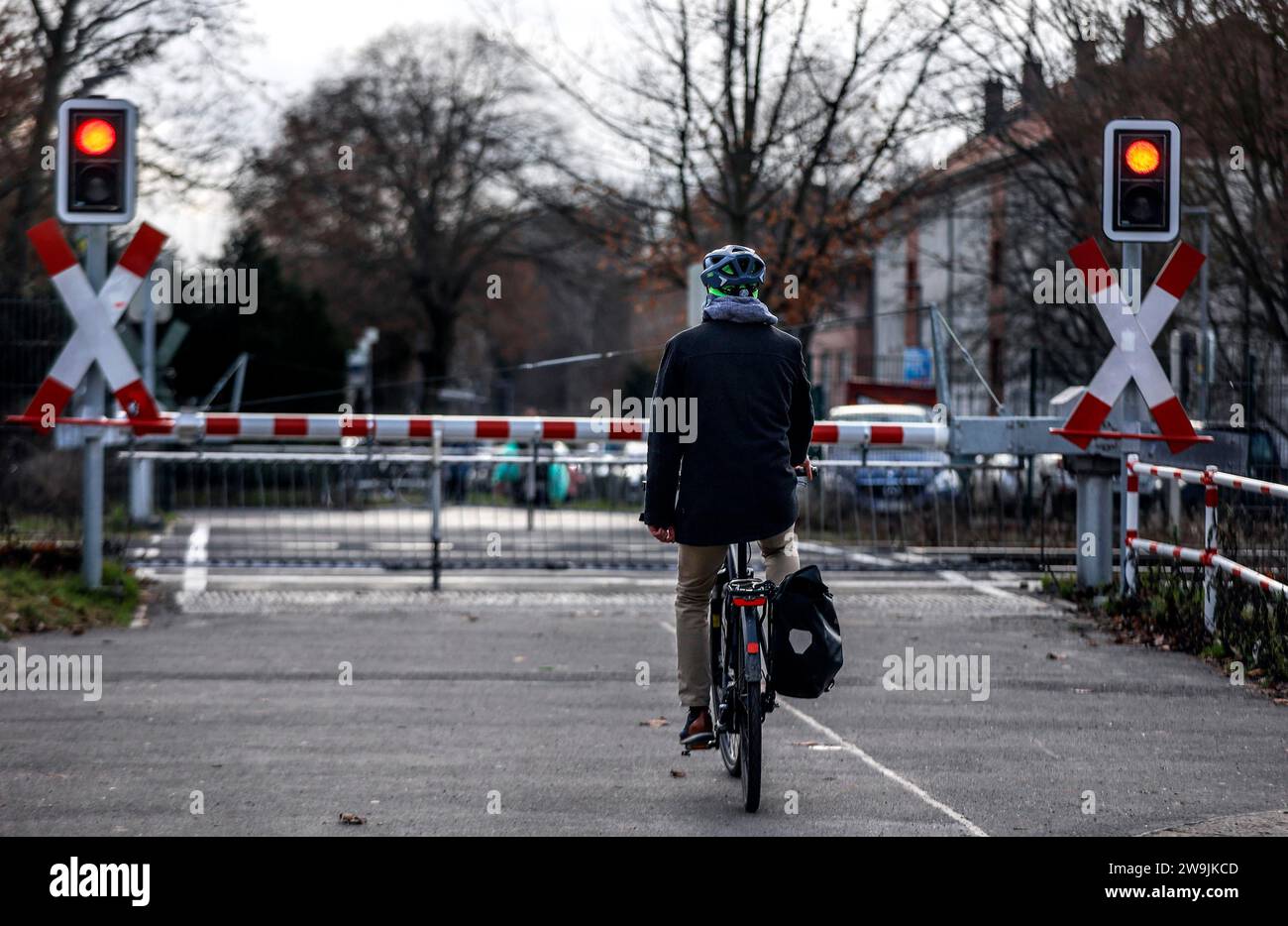 Un cycliste attend à un passage à niveau avec une barrière, Berlin, 10 01 2023 Banque D'Images