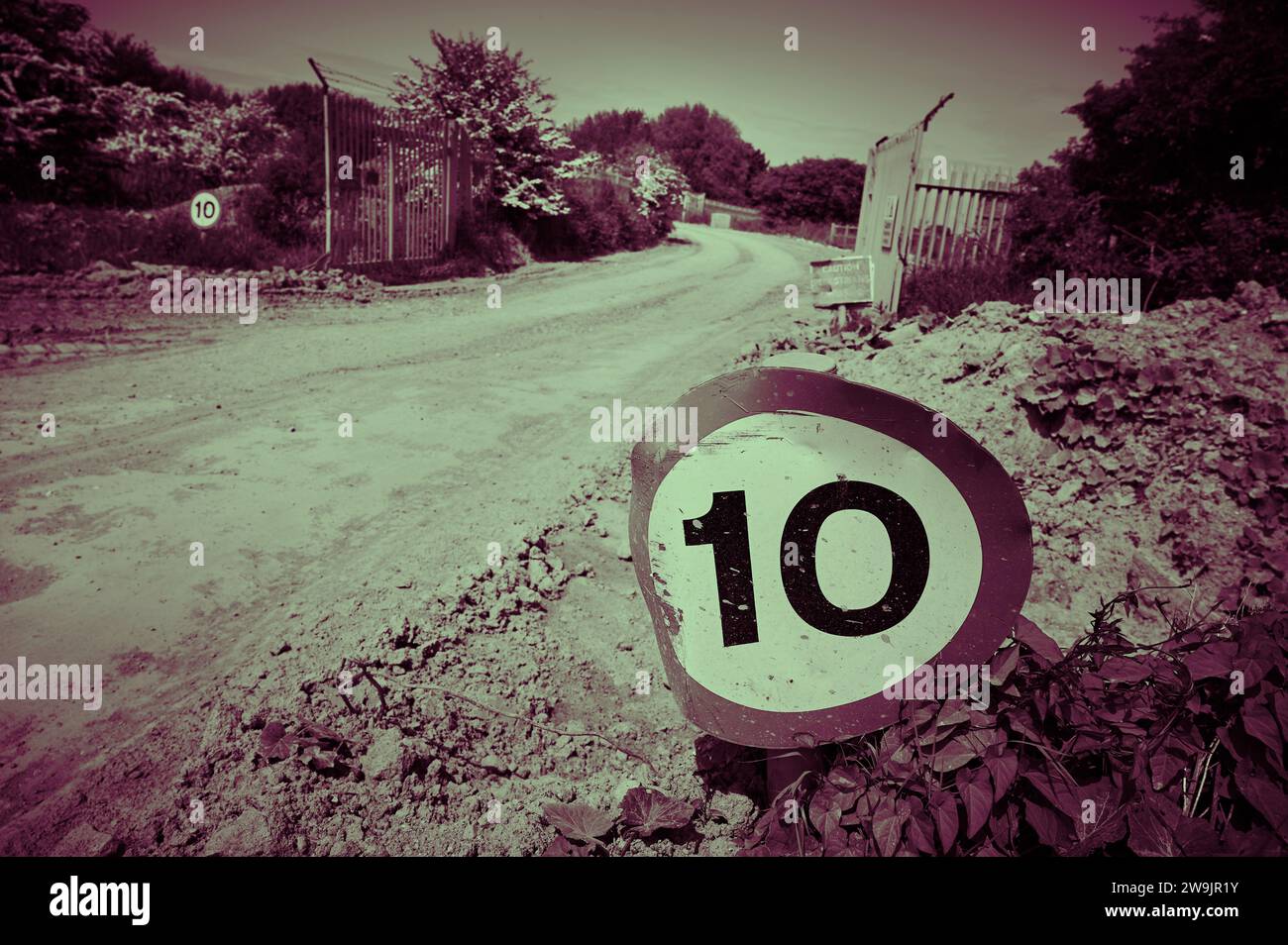 Panneau de limitation de vitesse sur route recouverte de boue sur site industriel Banque D'Images