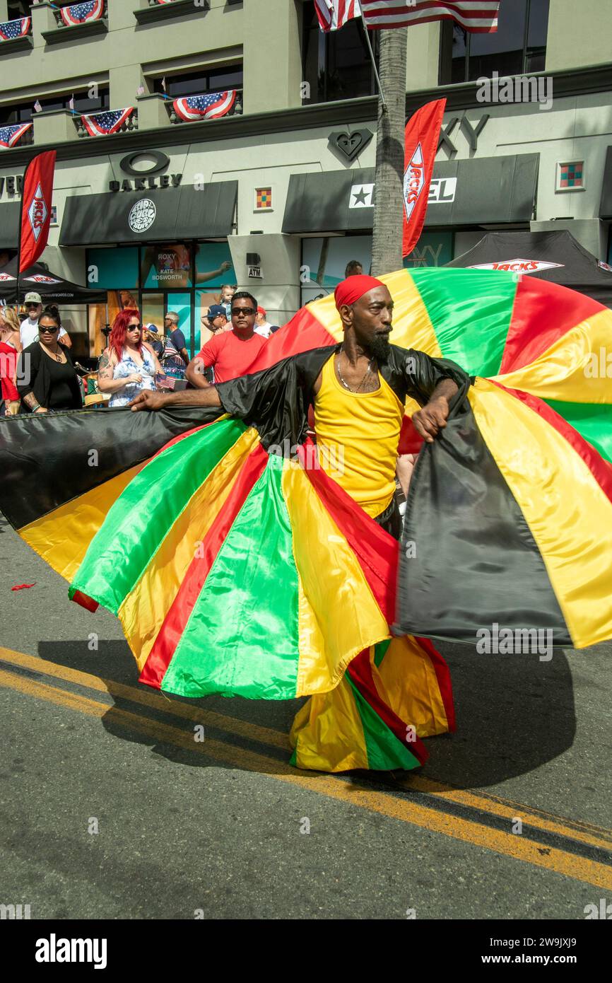 Tourbillonnant son costume, un danseur afro-caribéen marche dans un défilé du 4 juillet à Huntington Beach, en Californie. Banque D'Images