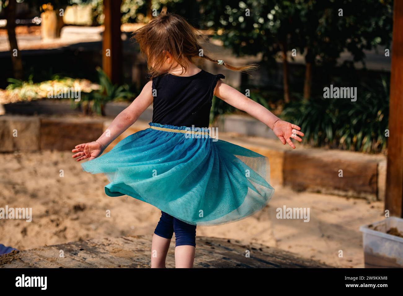 Petite fille tournoyant dans la robe bleu vif à l'école maternelle Banque D'Images