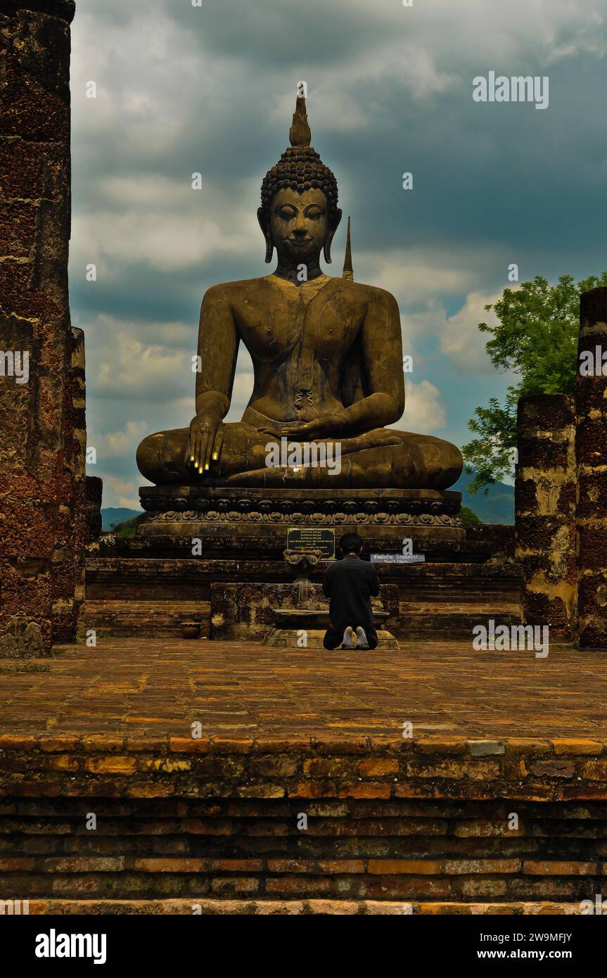 Homme priant Bouddha à Wat Mahathat, parc historique de Sukhothai Banque D'Images