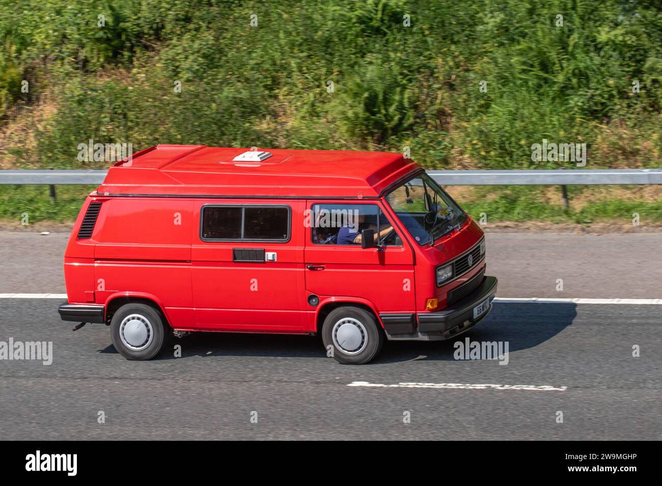 Années 1990 90 Nineties Rouge VW Volkswagen car Grand monospace essence 1915 cc campervan ; transporter, camping-cars, kombi, combi, campervan van, conversion camping-car, Vee Dub, conversions, microbus, bus, camping-cars, fourgonnettes VW, camping-cars Volkswagen roulant sur la M6 à Manchester, Royaume-Uni Banque D'Images