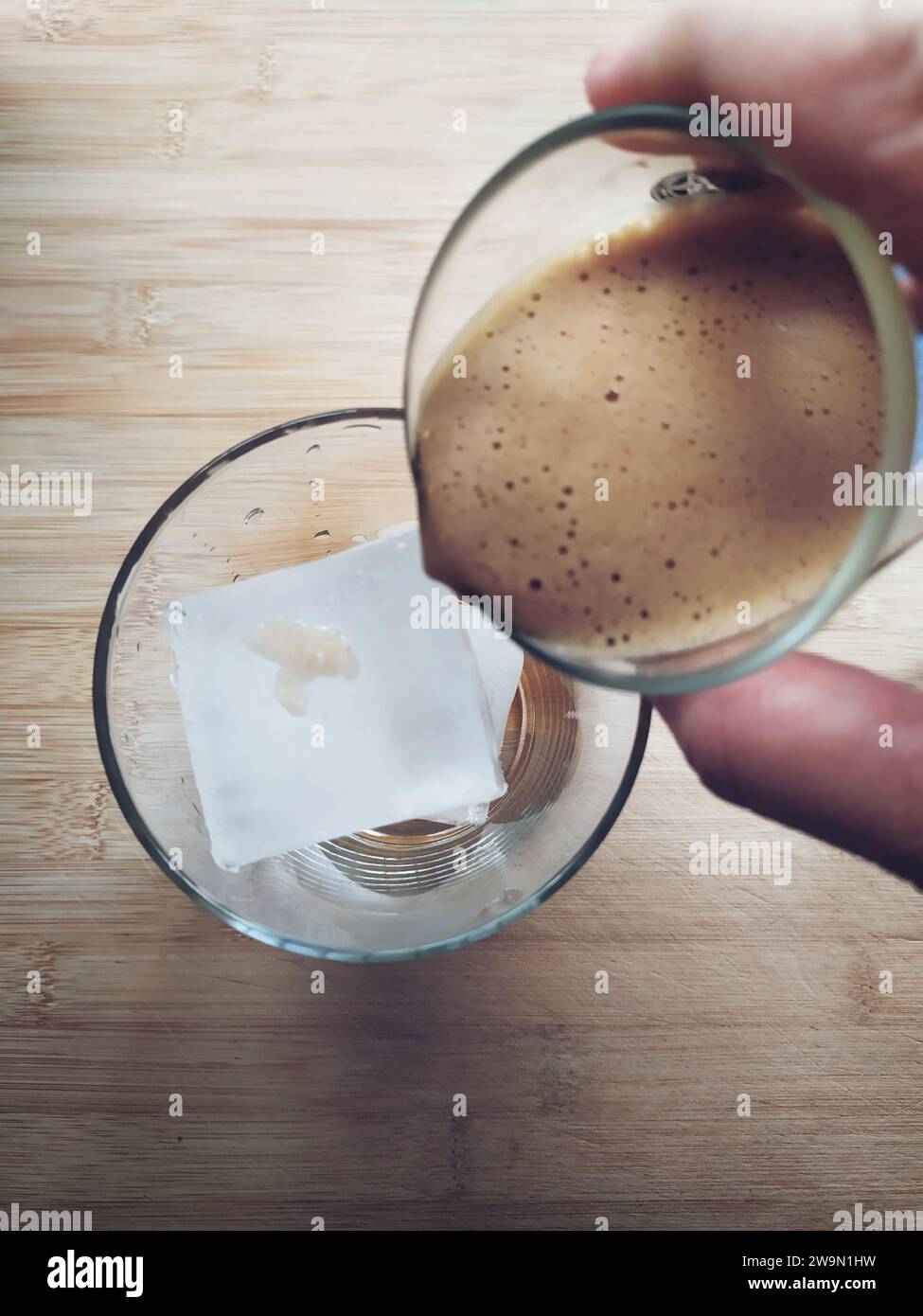 Vue aérienne d'une personne versant une dose d'espresso sur un glaçon pour préparer un café glacé Banque D'Images