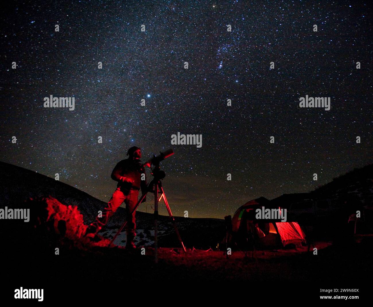 Un homme se tient près de son télescope avec en toile de fond la voie lactée galaxie. White Hills, Californie. Banque D'Images