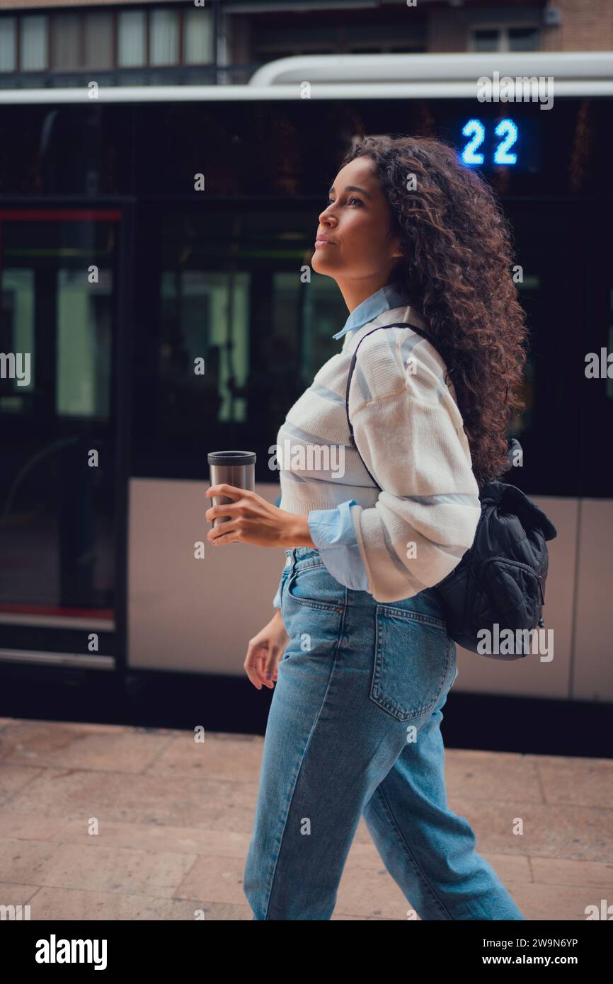 Femme sud-américaine aux cheveux bouclés buvant du café dans la rue Banque D'Images