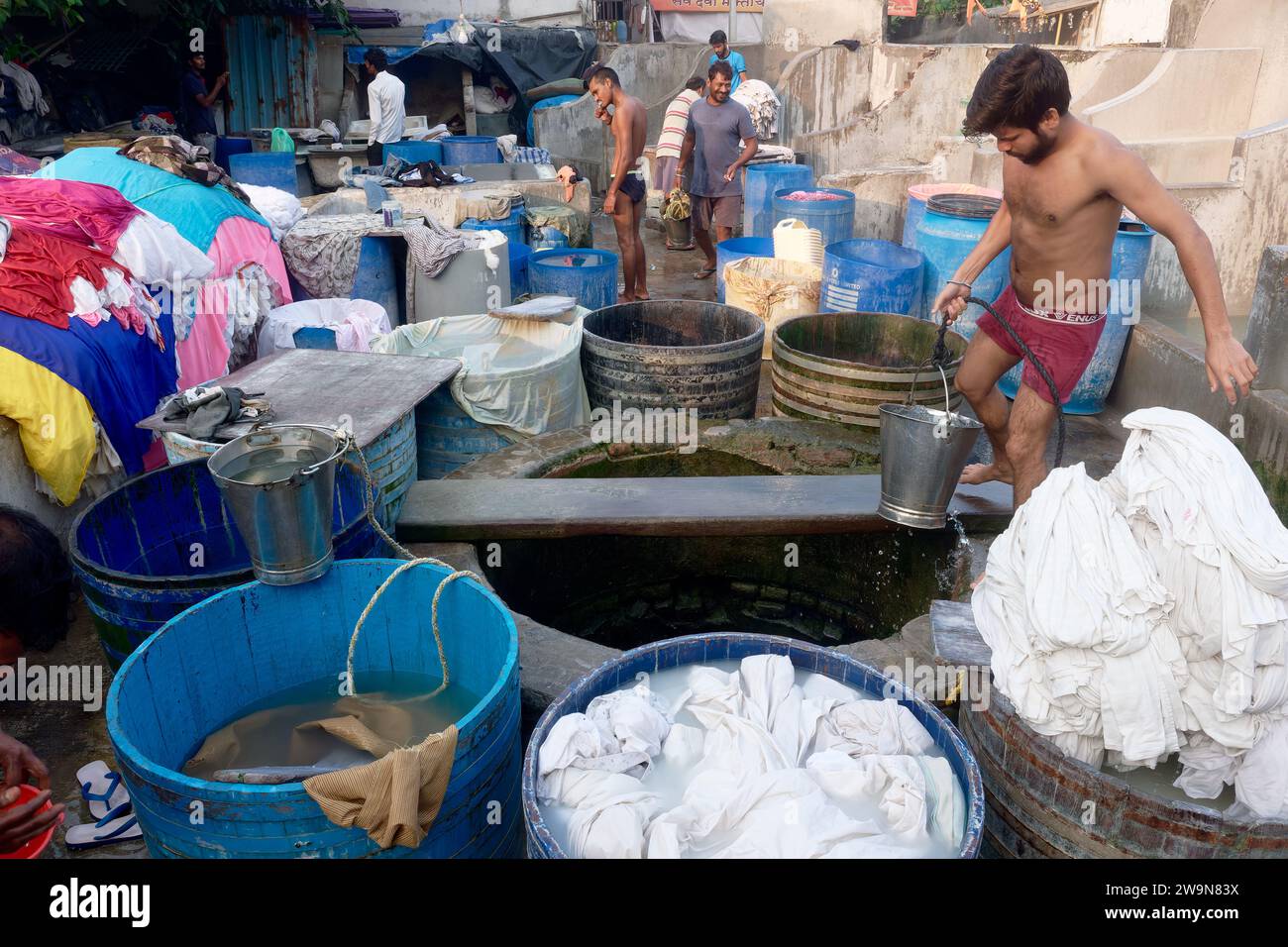 Un dhobi (laveur) à Walkeshwar Dhobi Ghat, une buanderie traditionnelle en plein air, tire l'eau du puits de la région. À Walkeshwar, Mumbai, Inde Banque D'Images