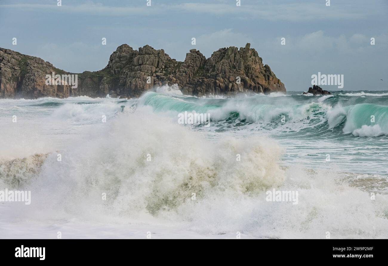 De grosses vagues se brisent sur la plage de Porthcurno, en Cornouailles, avec le rocher Logan en arrière-plan alors que la tempête Gerrit traverse à Noël 2023 Banque D'Images