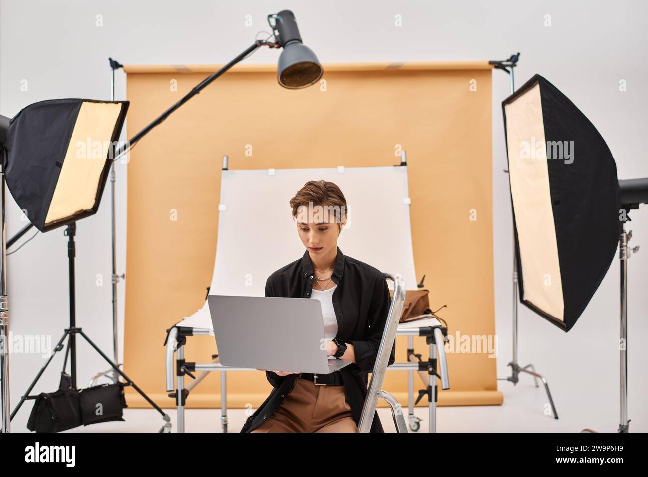 photographe aux cheveux courts séduisante assise et retouchant des photos dans son studio à l'aide de son ordinateur portable Banque D'Images