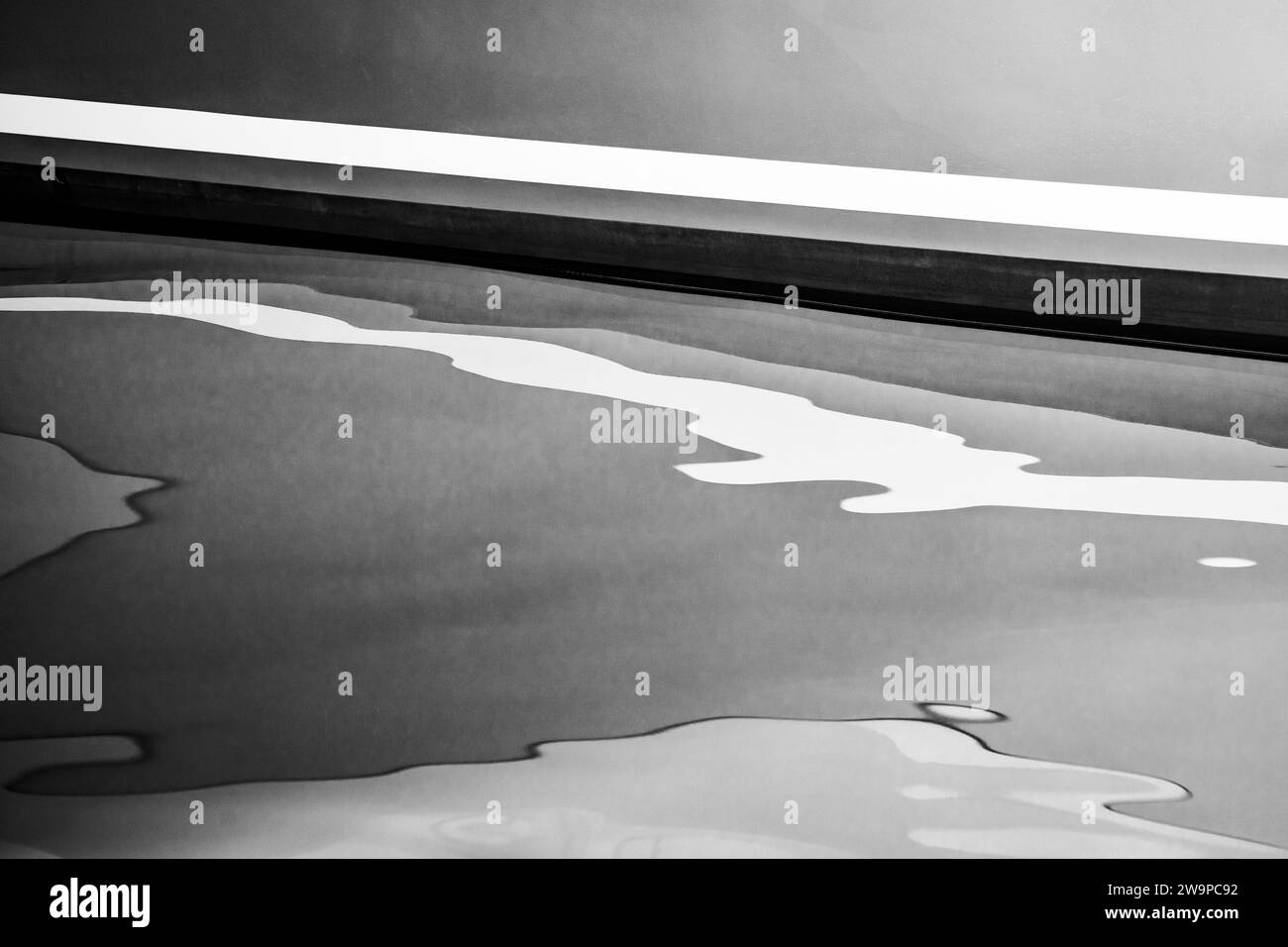 Image en noir et blanc d'une coque de yacht réfléchissant sur l'eau calme. Banque D'Images