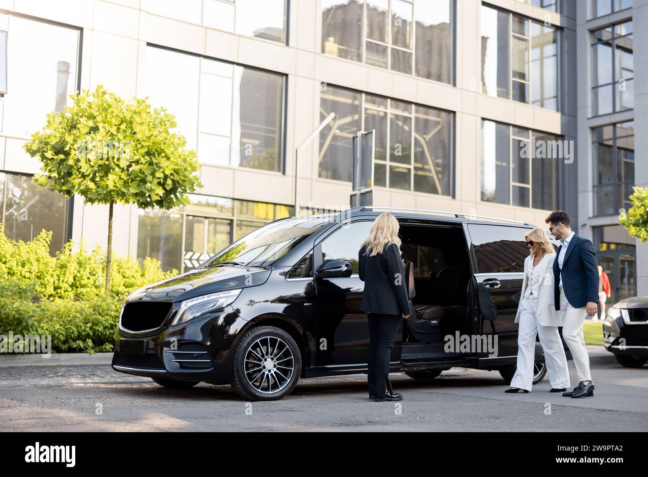 Femme chauffeur attend un gens d'affaires près de minivan taxi Banque D'Images