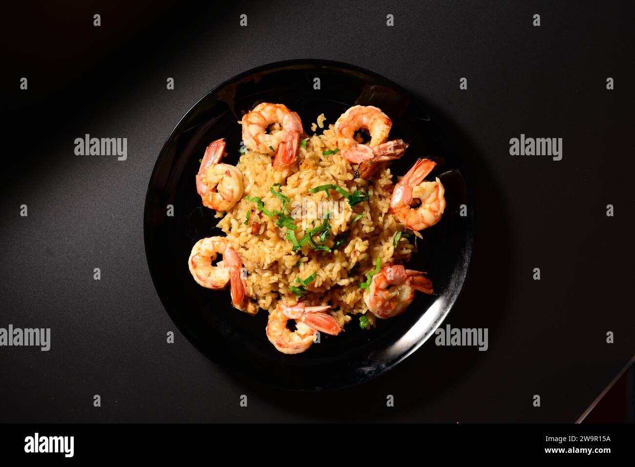 Risotto aux moules et crevettes sur une assiette noire. Banque D'Images