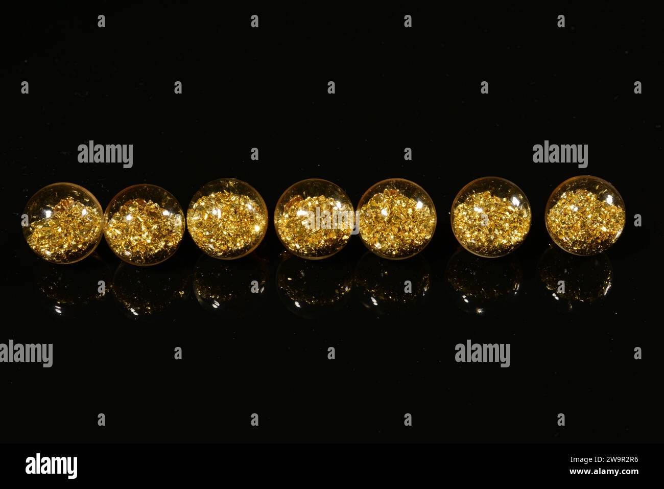 perles avec paillettes dorées sur un fond miroir noir. Banque D'Images
