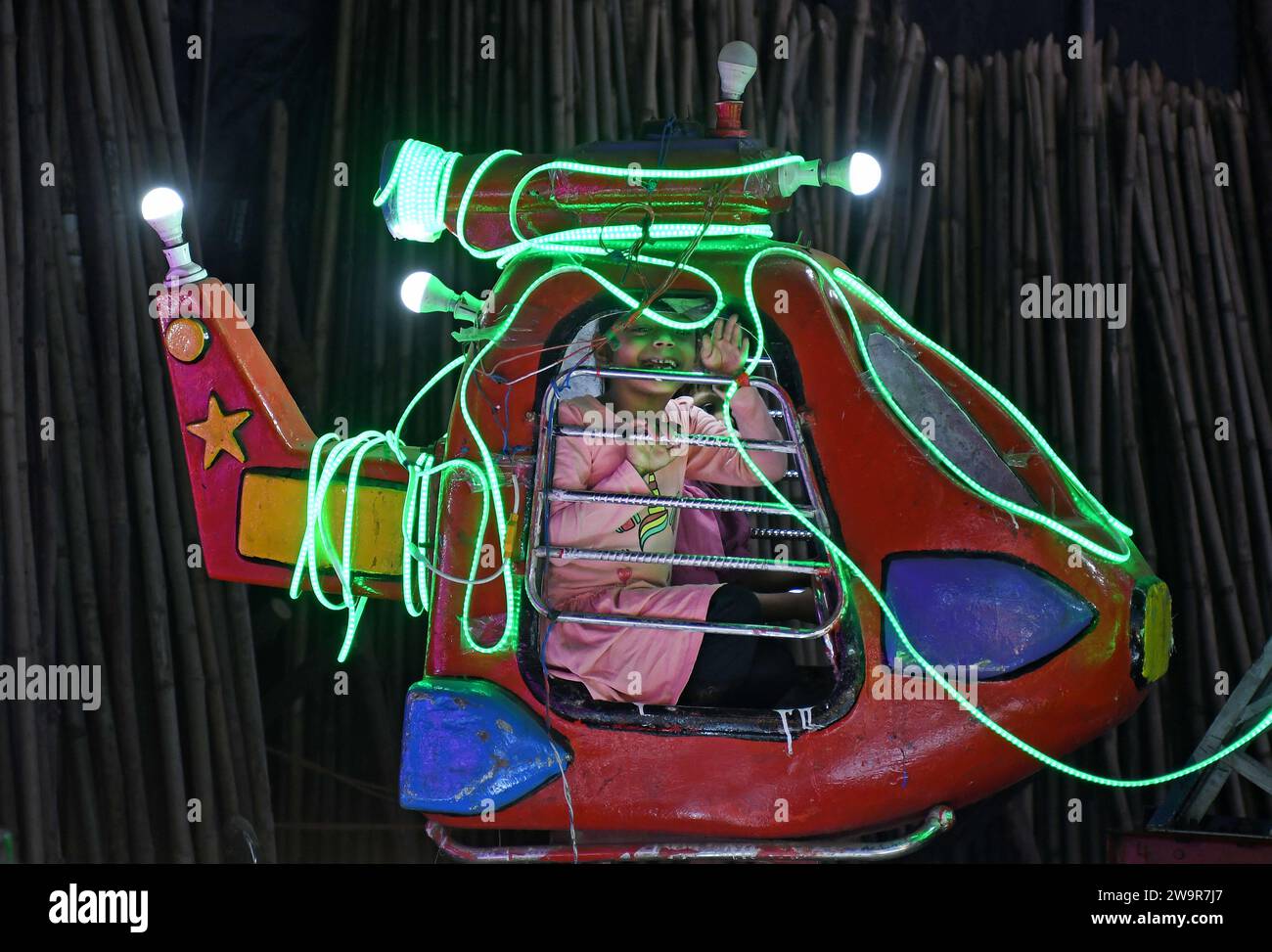 Une fille fait des vagues comme elle aime le tour d'attraction d'hélicoptère à Mahim (zone dans le sud de Mumbai) foire à Mumbai. Une foire annuelle est organisée chaque année pour honorer Pir Makhdoom Shah (saint spirituel musulman) vénéré par les musulmans et les non-musulmans. L'événement de dix jours aura lieu du 27 décembre 2023 au 7 janvier 2024 offrant une variété de manèges alimentaires et d'attractions. Banque D'Images