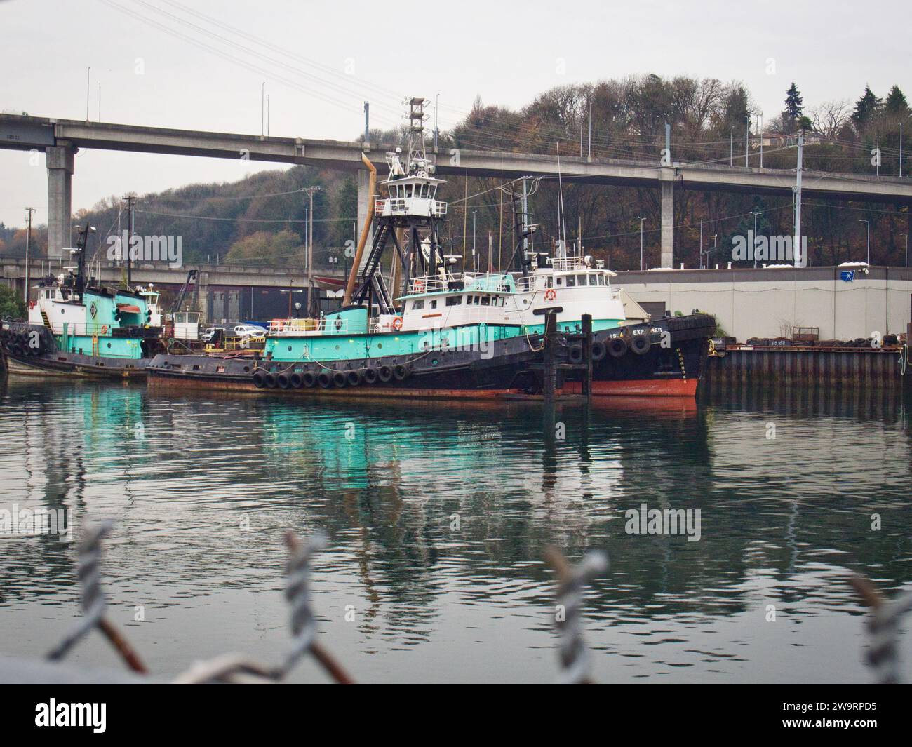 Un bateau bleu ancré dans le canal portuaire près de Harbor Island à Seattle, Washington par une sombre journée d'hiver. Banque D'Images