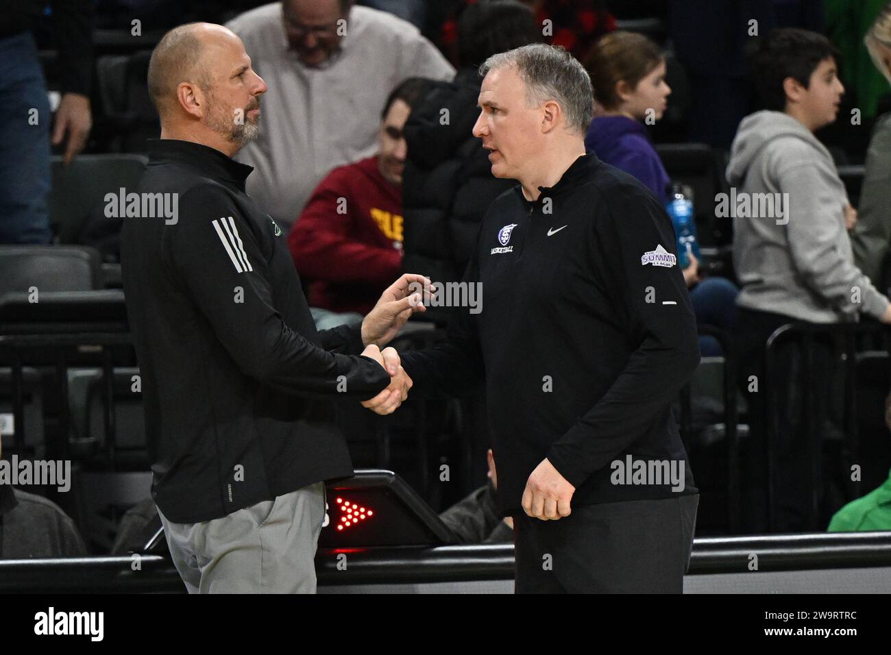 L'entraîneur-chef des Fighting Hawks du Dakota du Nord Paul Sather (à gauche) serre la main de St. Thomas Tommies entraîneur-chef Johnny Tauer après un match de basket-ball masculin de la NCAA entre l'Université de St. Thomas Tommies et l'Université du Dakota du Nord combattent des faucons au Betty Engelstad Sioux Center à Grand Forks, Dakota du Nord, le vendredi 29 décembre 2023. St. Thomas a gagné 70-45. Russell Hons/CSM Banque D'Images