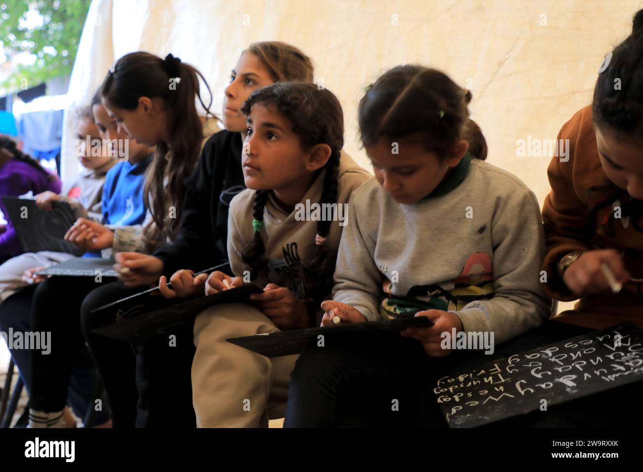 Pékin, Chine. 28 décembre 2023. Des étudiants étudient dans une salle de classe temporaire dans la ville de Rafah, dans le sud de la bande de Gaza, 28 décembre 2023. Certains étudiants de Gaza sont passés étudier dans des salles de classe temporaires car de nombreuses écoles sont utilisées ici pour accueillir les sans-abri infligés par une nouvelle vague de conflit israélo-palestinien. Crédit : Rizek Abdeljawad/Xinhua/Alamy Live News Banque D'Images