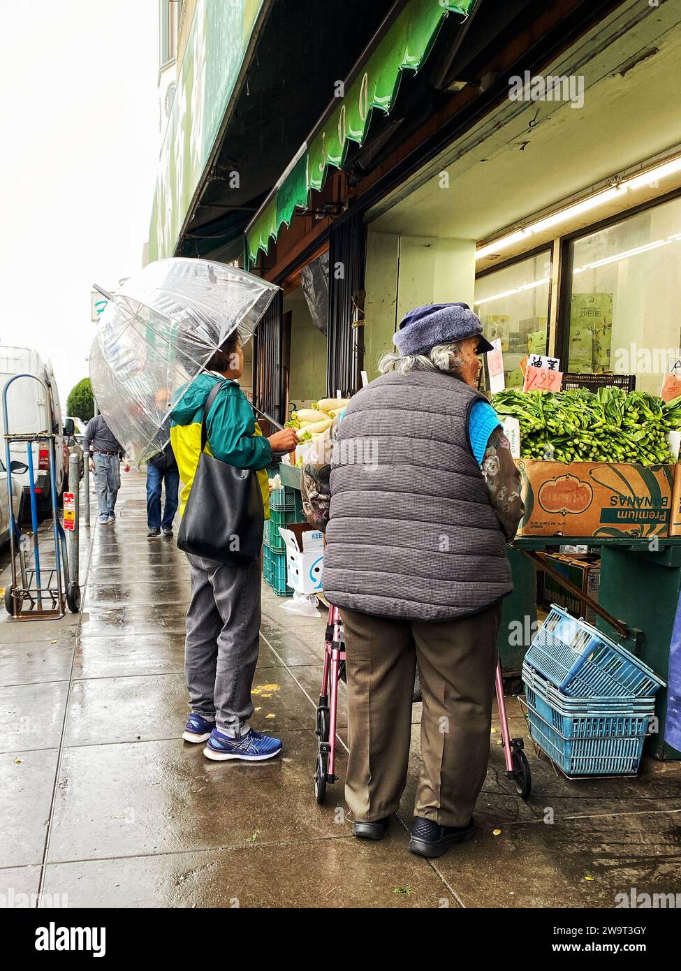 Deux femmes faisant des courses sous la pluie dans un marché extérieur à Chinatown, San Francisco, Californie Banque D'Images