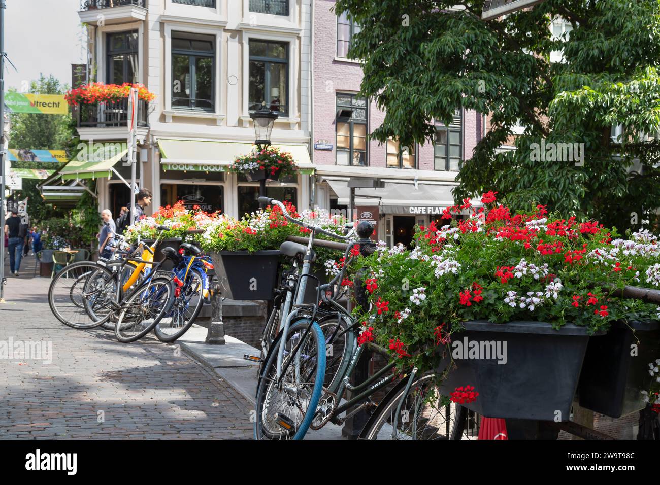Plusieurs vélos garés sur un pont avec des fleurs dans le centre de la ville d'Utrecht. Banque D'Images