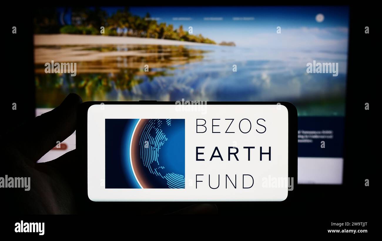 Personne tenant un smartphone avec le logo de l'organisation environnementale Bezos Earth Fund devant le site Web. Concentrez-vous sur l'affichage du téléphone. Banque D'Images