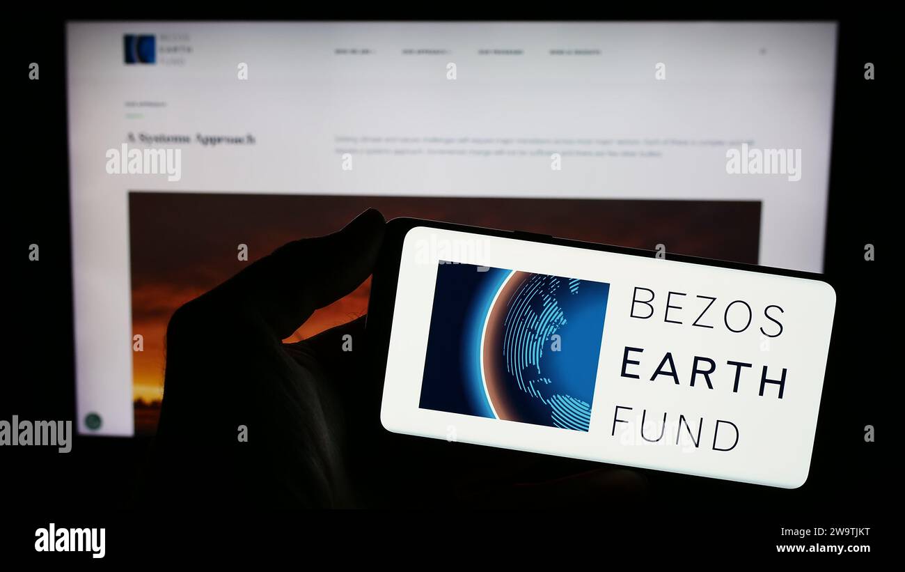 Personne tenant un téléphone portable avec le logo de l'organisation environnementale Bezos Earth Fund devant la page Web. Concentrez-vous sur l'affichage du téléphone. Banque D'Images