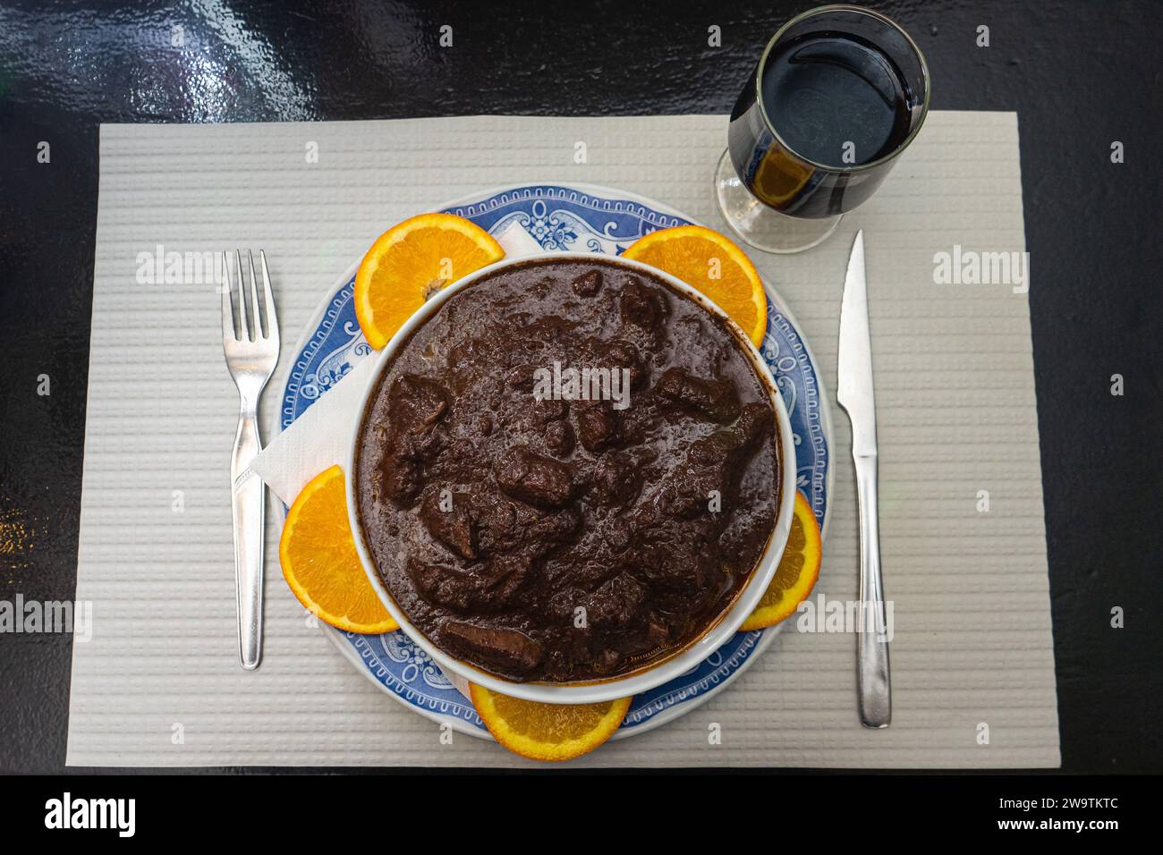 Le plat traditionnel de l'Alentejo, le Rechina, est servi avec un verre de vin rouge dans un restaurant rustique. Banque D'Images