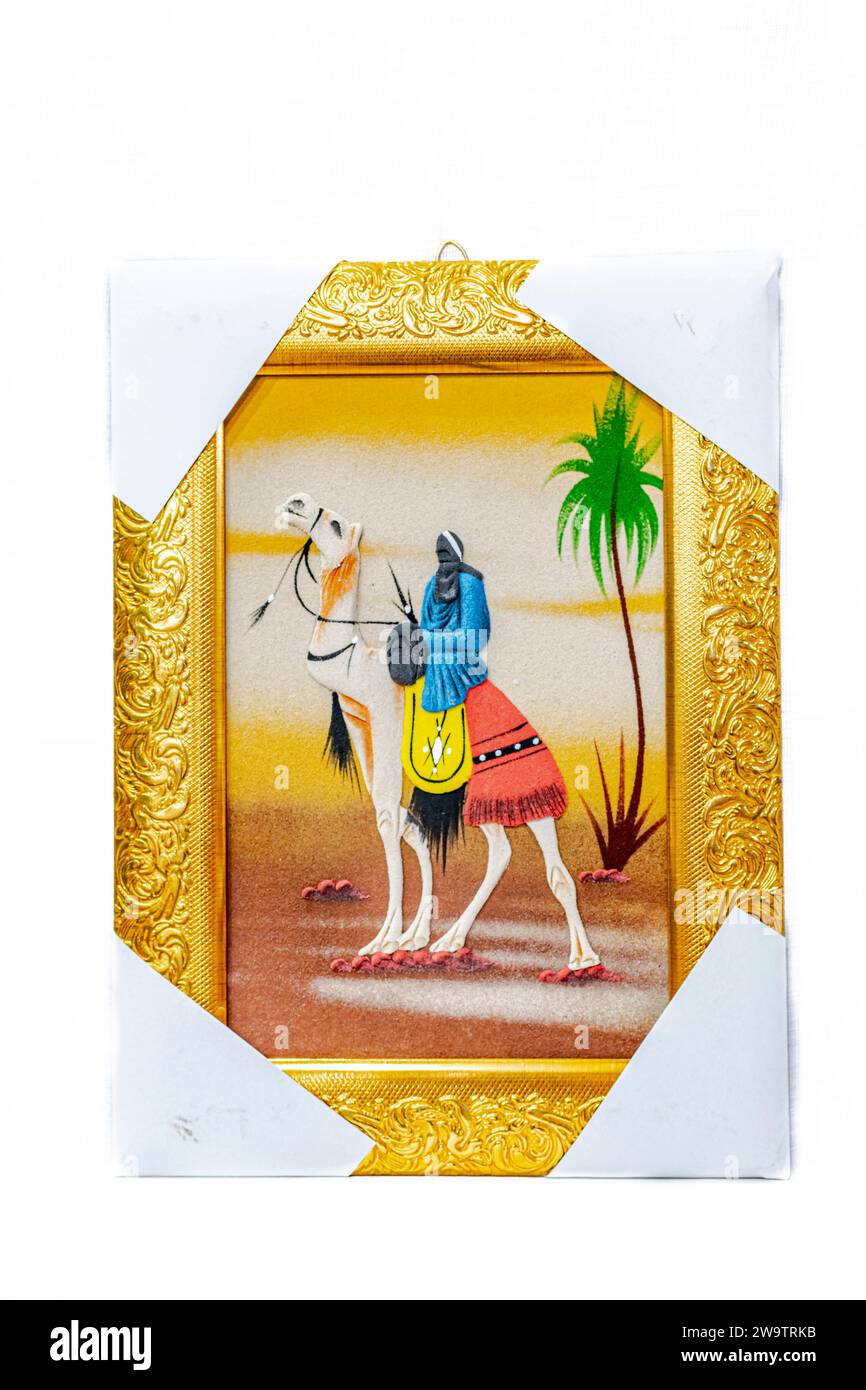 Une peinture sur sable avec un cadre en or, les coins protégés par du papier blanc, représente un cavalier sahraoui tenant une épée et portant un foulard traditionnel Banque D'Images