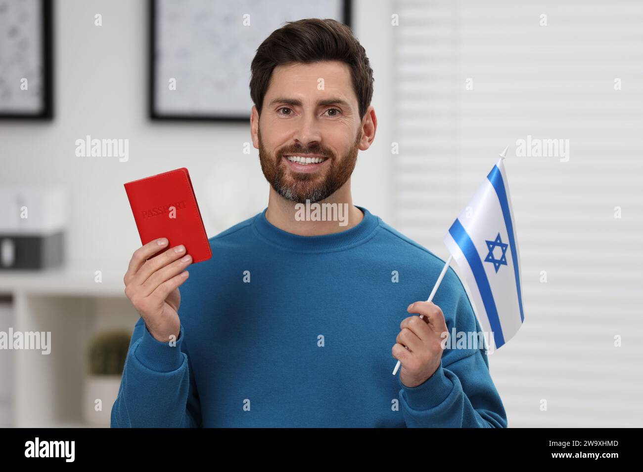 Immigration. Homme heureux avec passeport et drapeau d'Israël à l'intérieur Banque D'Images