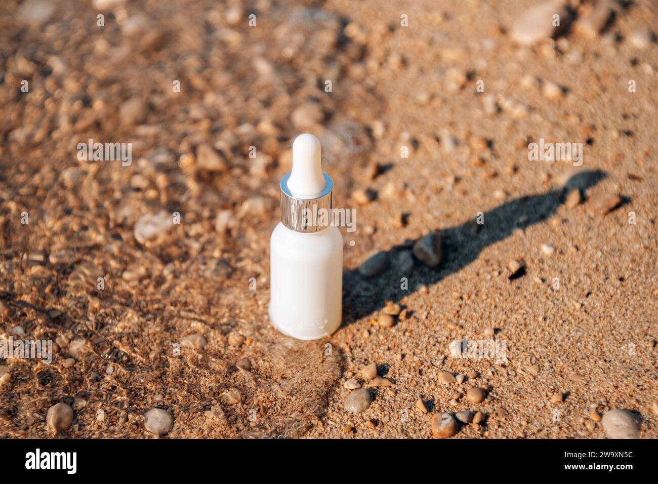 Acide hyaluronique, sérum soin de la peau bouteille blanche sur fond de plage de sable. Produit cosmétique de sérum avec peptide et collagène. Emballage de cosmétiques de marque moderne Banque D'Images