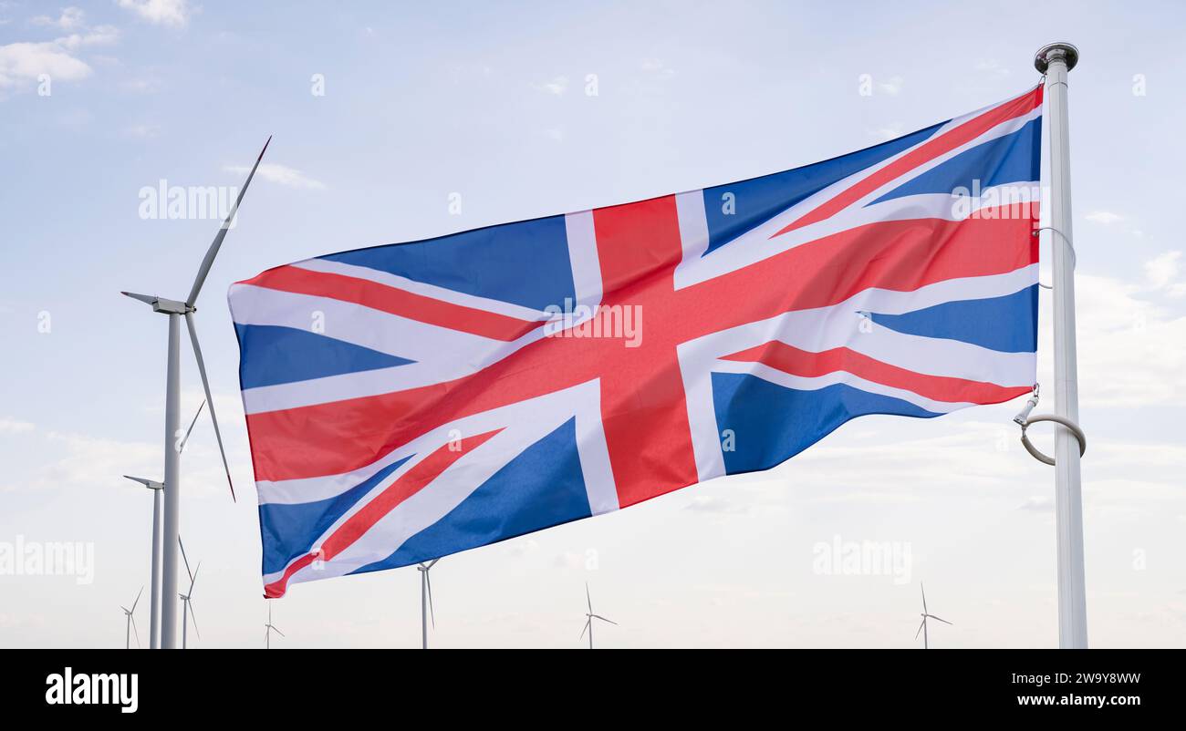 Le drapeau britannique flotte sur le backgorund des éoliennes. Symbole du développement durable Royaume-Uni. Banque D'Images