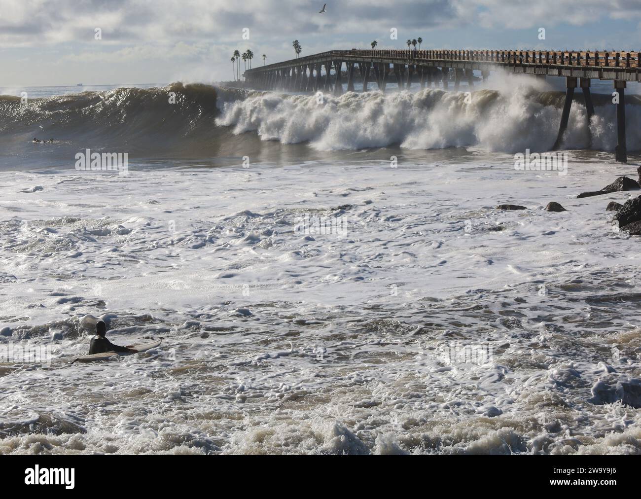 30 décembre 2023, Santa Barbara/Ventura, Californie, États-Unis : un surfeur solitaire, silhouette dans le surf, fait face au monstre, King Tidal Waves à la belle Rincon point, au sud de Carpinteria dans le comté de Santa Barbara et juste au nord de Ventura, le 30 décembre 2023. Le Rincon Pier est poussé derrière lui. Nuages de la même couleur que les vagues font une scène dramatique et belle. (Image de crédit : © Amy Katz/ZUMA Press Wire) USAGE ÉDITORIAL SEULEMENT! Non destiné à UN USAGE commercial ! Banque D'Images