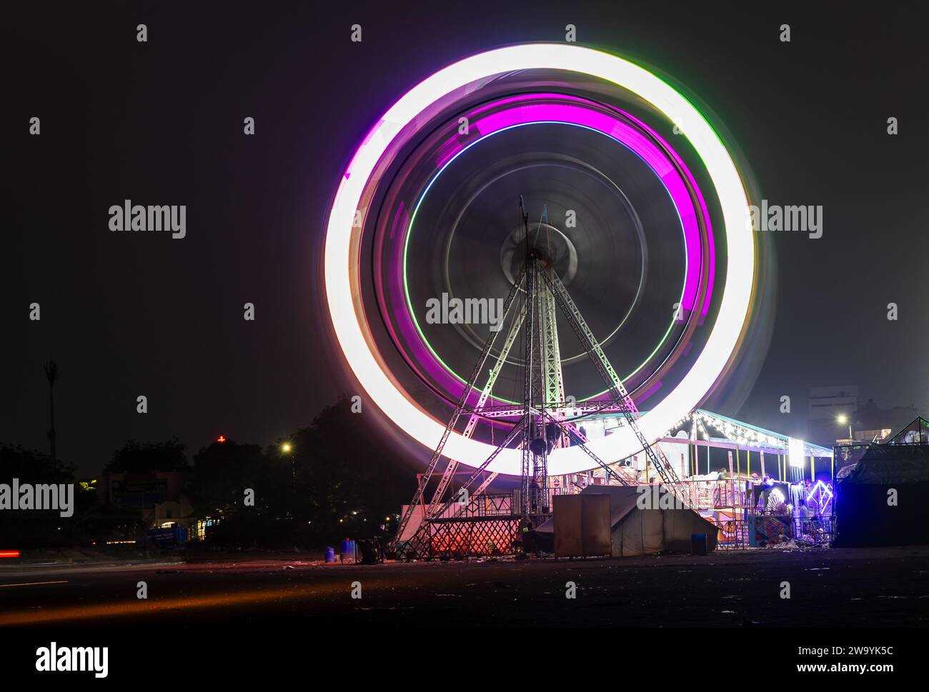 joyeuse balançoire ronde la nuit avec lumière colorée sur le terrain de foire de la ville et bavure de mouvement d'exposition longue Banque D'Images