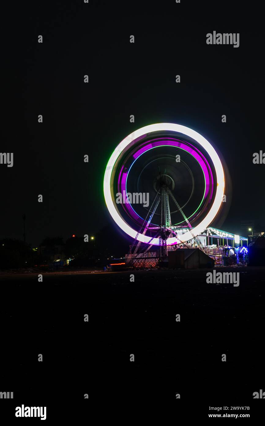 joyeuse balançoire ronde la nuit avec lumière colorée sur le terrain de foire de la ville et bavure de mouvement d'exposition longue Banque D'Images