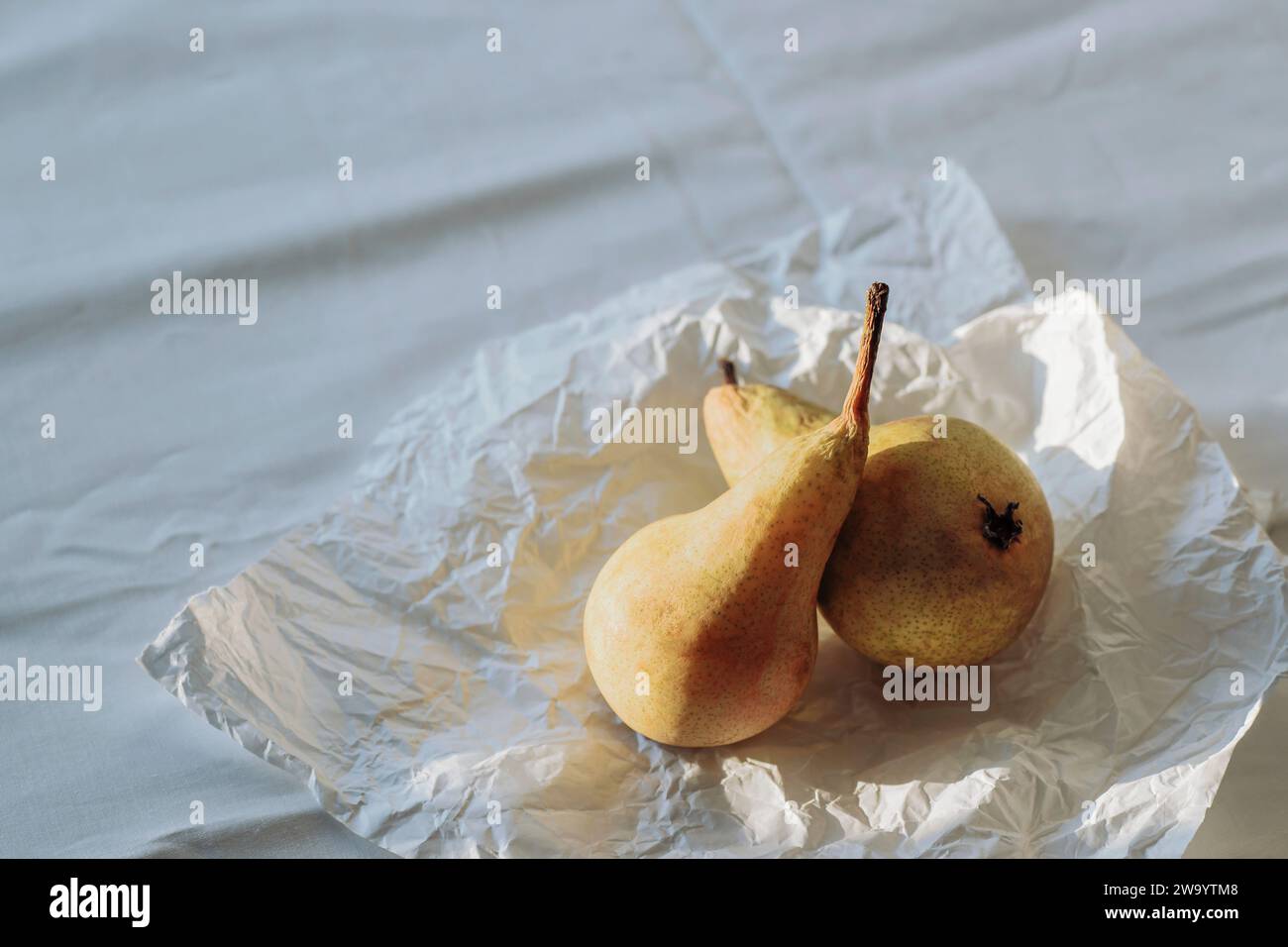 Deux fruits de poire sur le drap de lit au soleil. Nature morte d'été ou d'automne. Vue de dessus. Banque D'Images