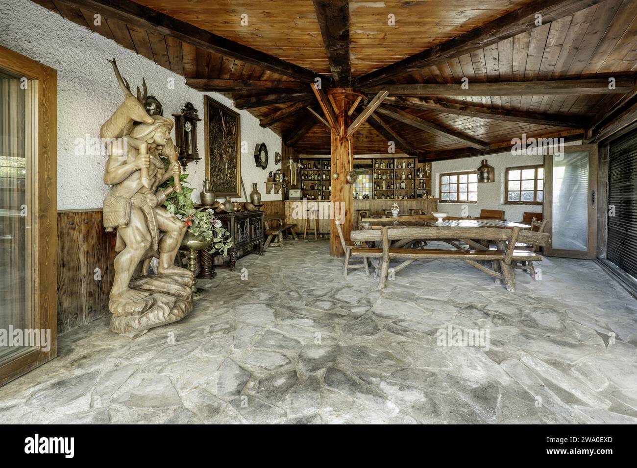 Un grand abri de jardin avec des meubles rustiques en bois, un bar avec des boissons et des détails décoratifs originaux Banque D'Images