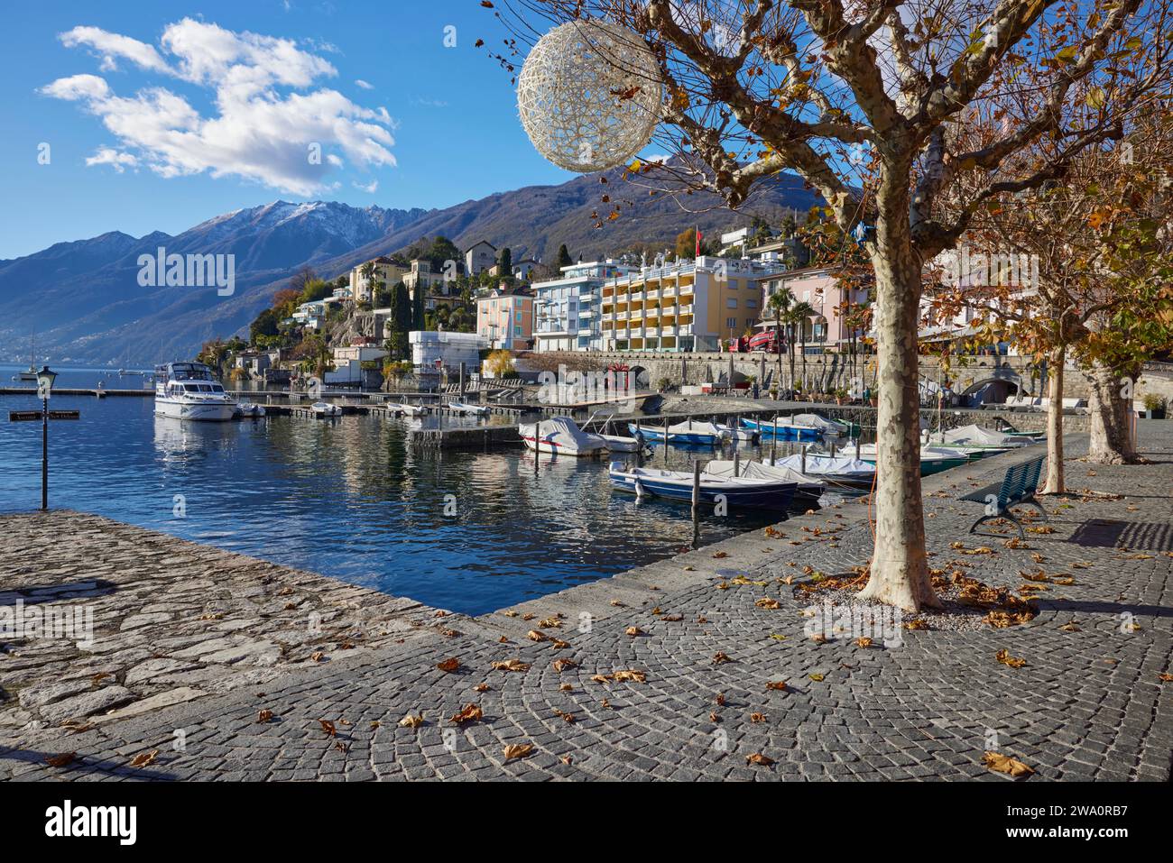 Vue sur le lac majeur en direction de Ronco sopra Ascona avec des bateaux à moteur et un platane (Platanus) de Lungolago, au bord du lac à Ascona, district Banque D'Images