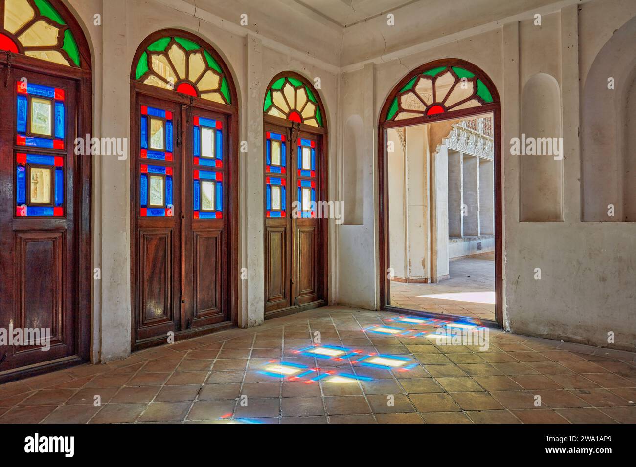 Vieilles portes en bois avec des vitraux colorés dans l'une des chambres de la Maison Tabatabaei, un manoir historique construit vers 1880 à Kashan, en Iran Banque D'Images