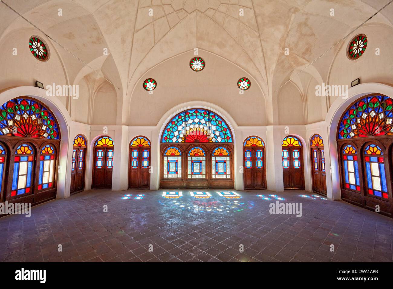 Grande chambre avec des vitraux colorés dans la Maison Tabatabaei, un manoir historique construit vers 1880 à Kashan, Iran. Banque D'Images