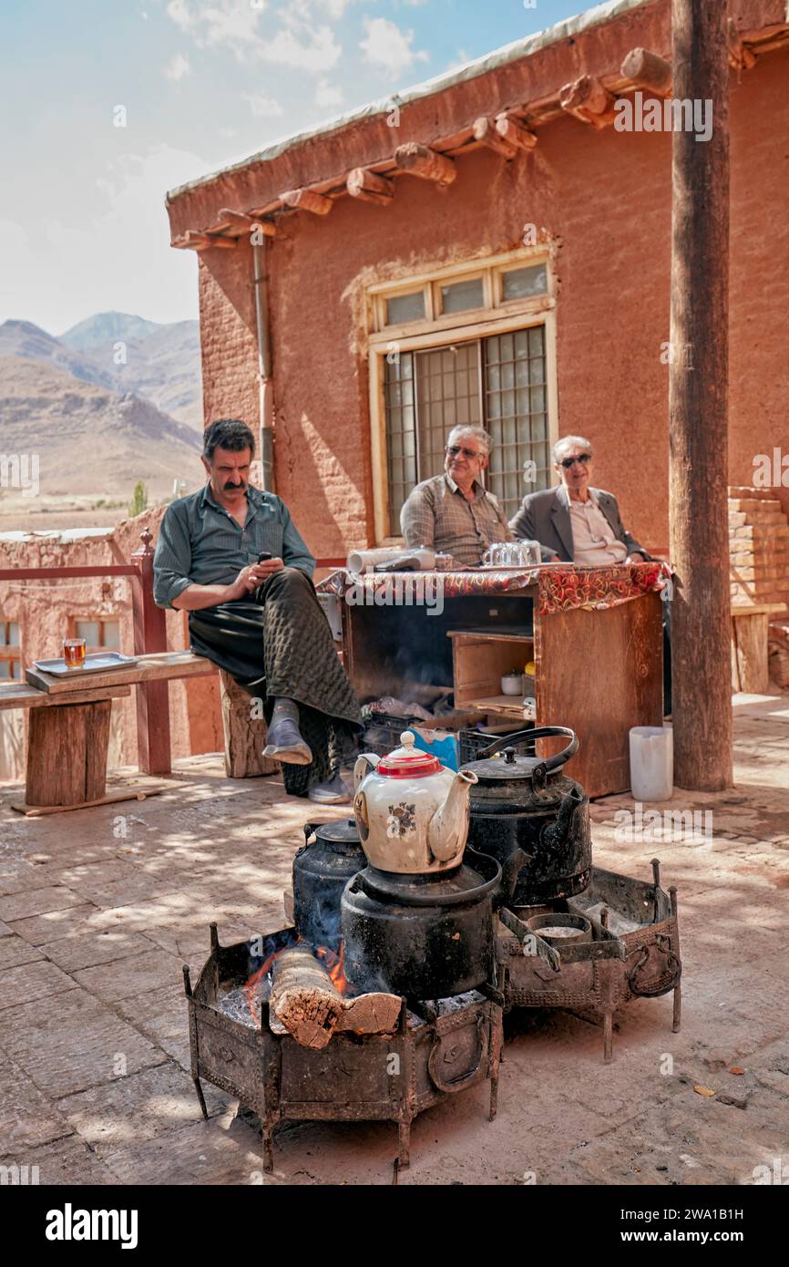 Les gens sont assis dans un petit salon de thé de rue pendant que leur thé est fait de manière traditionnelle sur un feu ouvert. Village d'Abyaneh, comté de Natanz, Iran. Banque D'Images