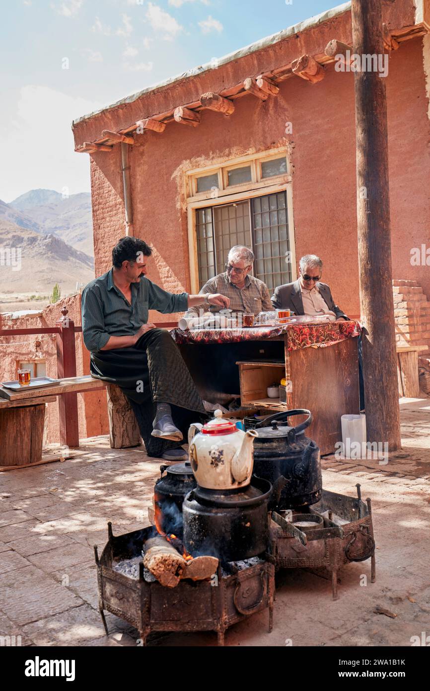 Le vendeur de rue sert du thé frais préparé de manière traditionnelle sur un feu ouvert à ses clients. Village d'Abyaneh, comté de Natanz, Iran. Banque D'Images