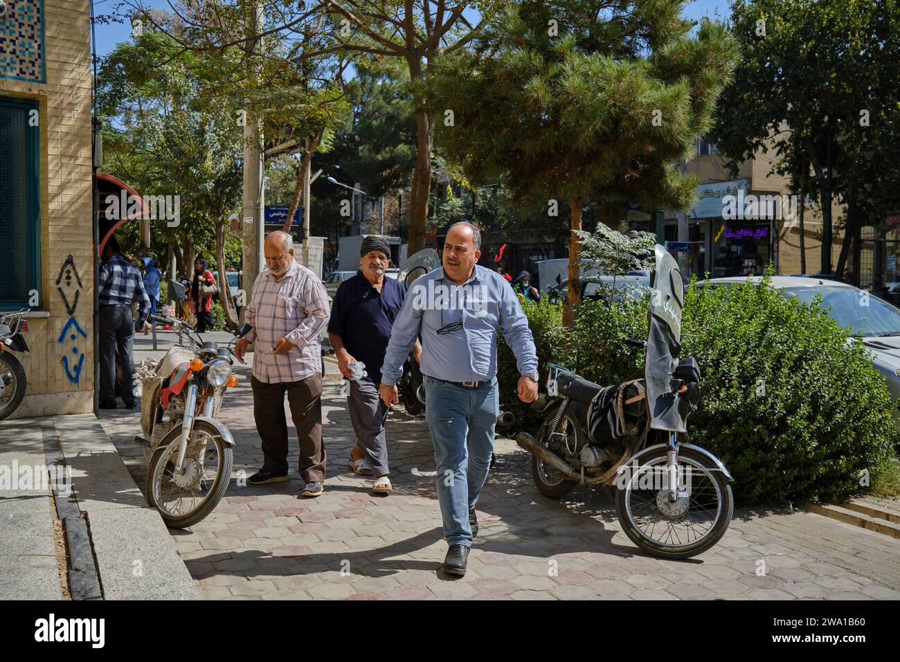 Hommes marchant sur le trottoir le long de la rue Baba Afzal à Kashan, Iran. Banque D'Images