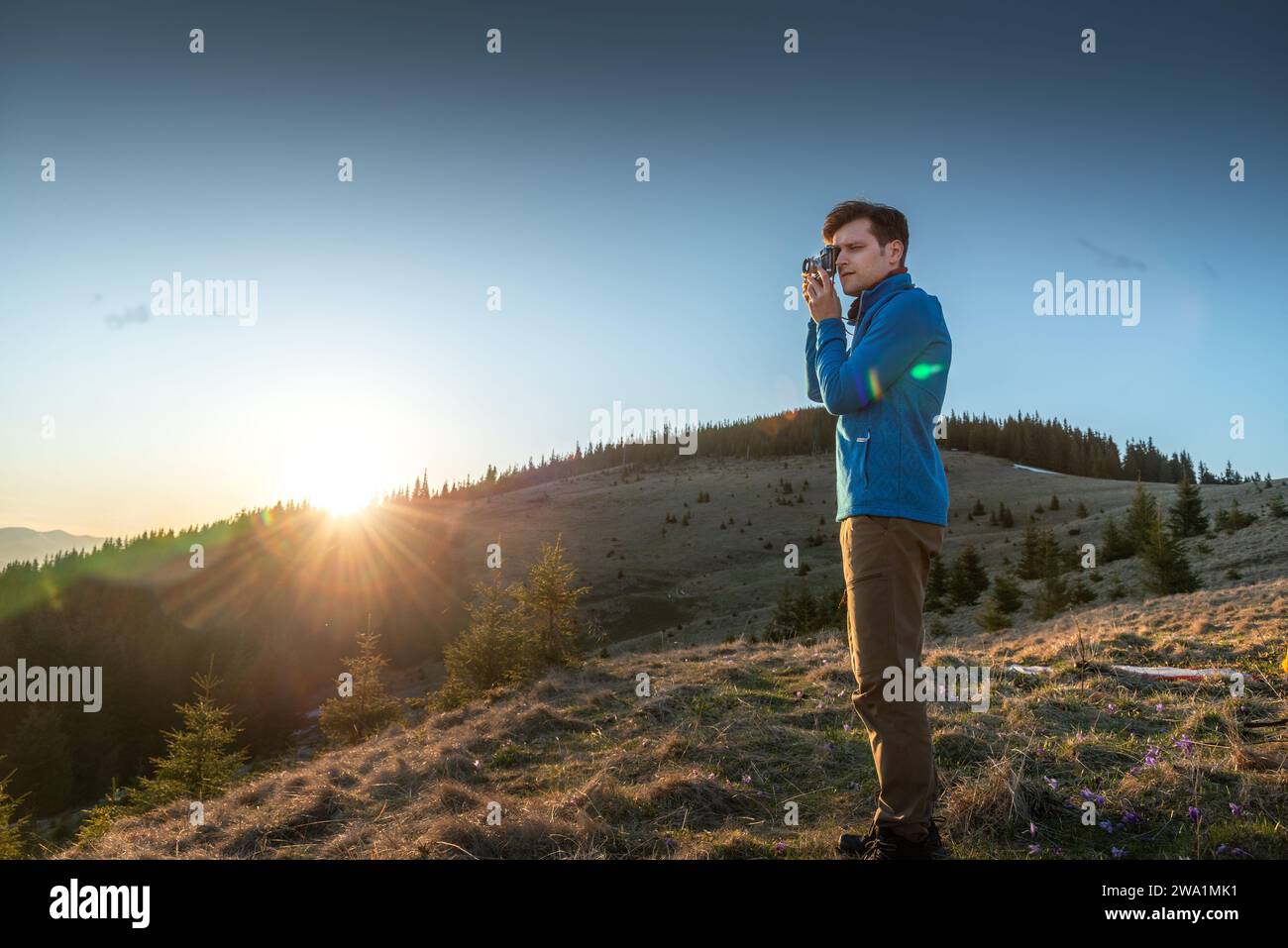 Jeune homme photographiant une belle vue au coucher du soleil Banque D'Images