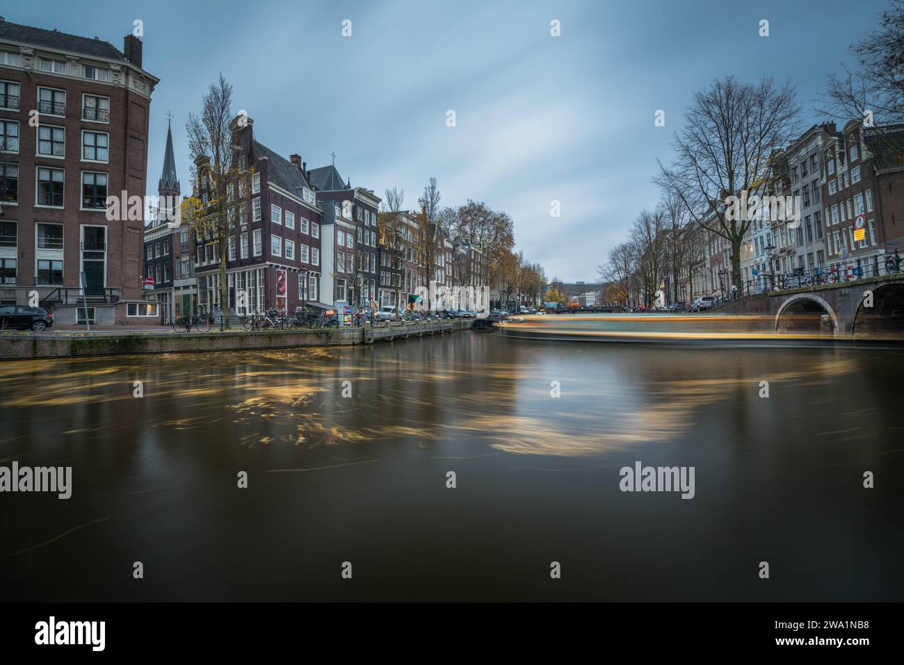 Long canal d'exposition avec bateau strié et nuages sombres à Amsterdam Banque D'Images