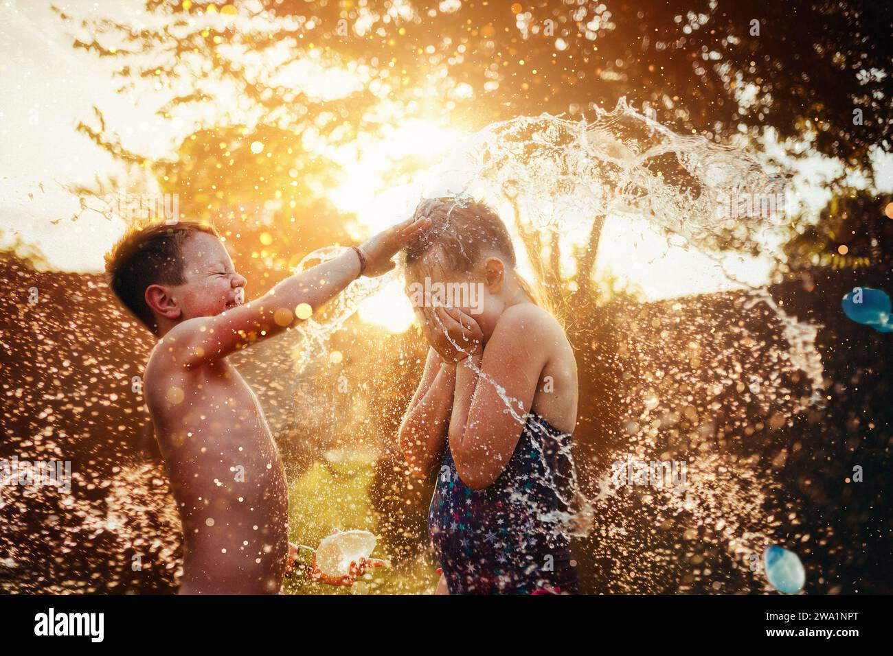 Deux enfants jouant avec des ballons d'eau en été Banque D'Images