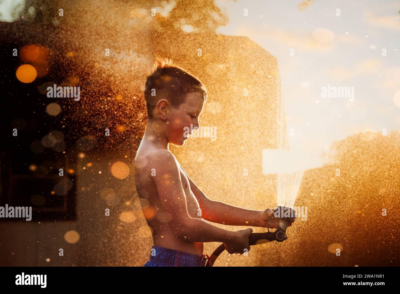 Garçon jouant dans l'eau devant la lumière dorée Banque D'Images