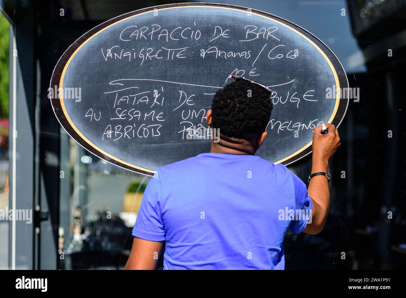 Un commis modifiant le menu sur le panneau à l'entrée du restaurant à Amiens | un commis modifie le menu sur le panneau a l'entrée du restaurant Banque D'Images